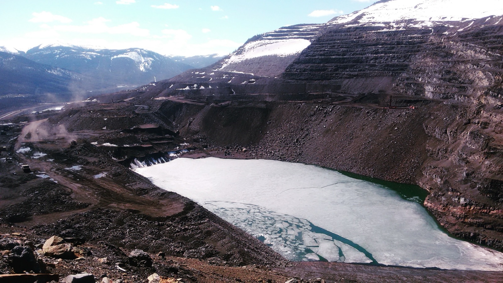 Open-pit mine with a turquoise frozen tailings pond
